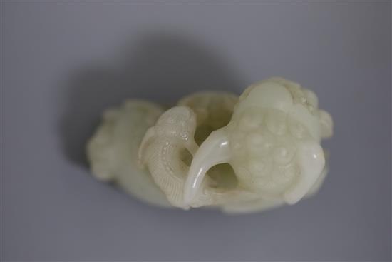 A Chinese pale celadon jade figure of a lion dog and cub, 18th/19th century, L. 6cm, wood stand